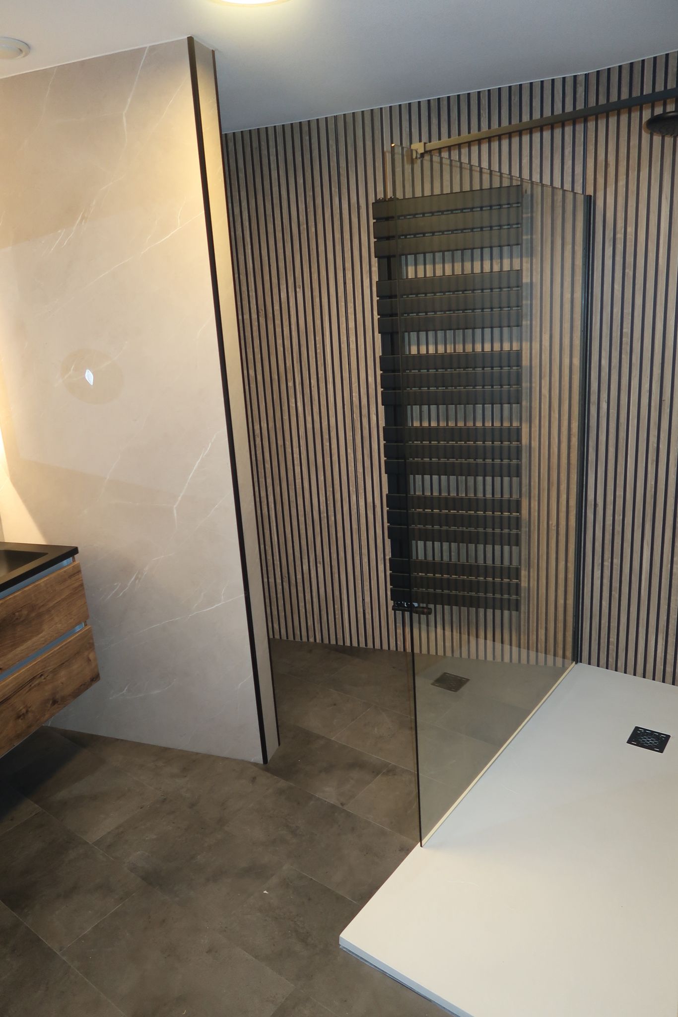 Moderne inloopdouche met houtlook wandpanelen en zwarte handdoekradiator